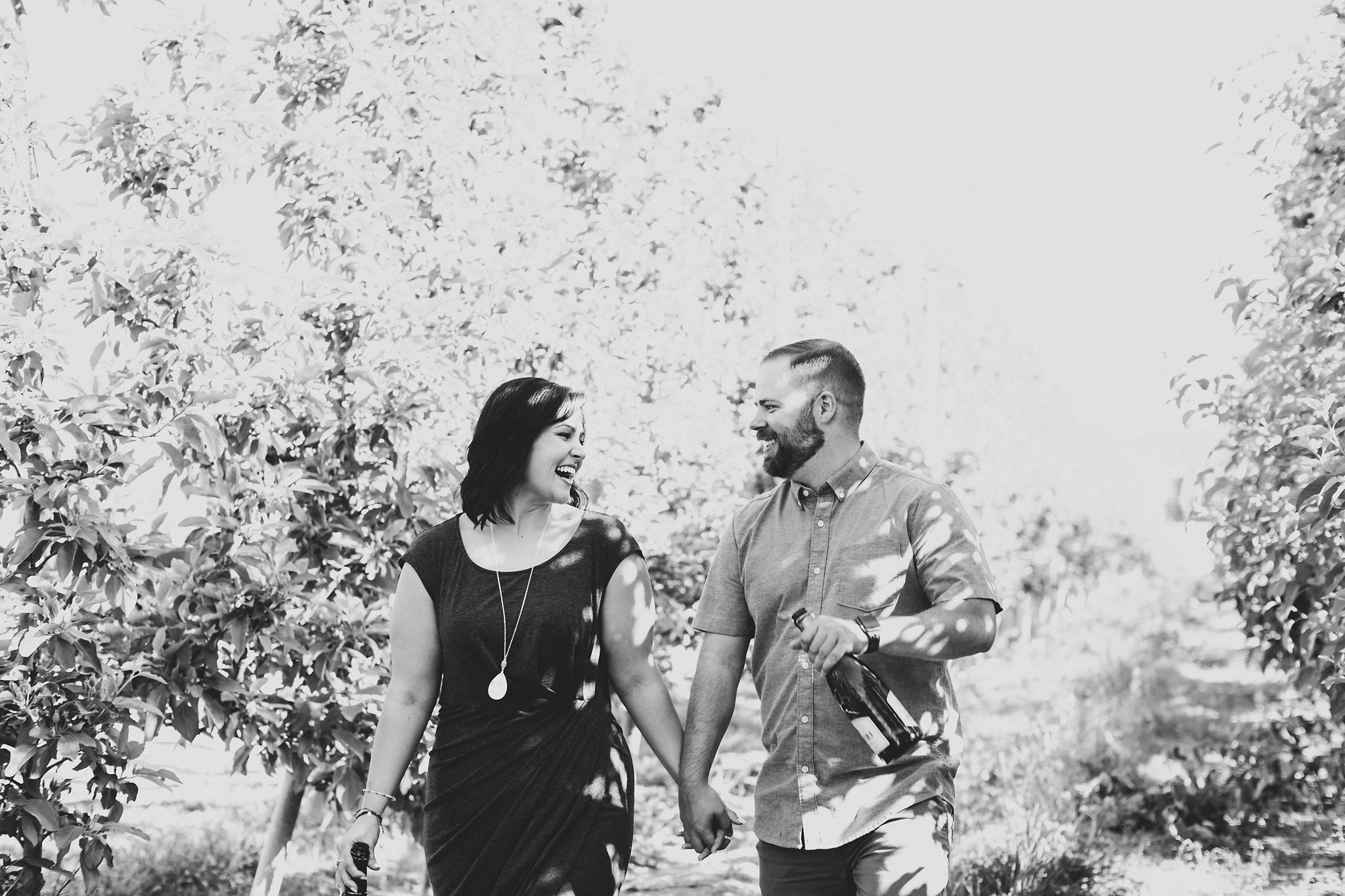 Engaged couple walking through an apple orchard at Treveri Cellars in Yakima