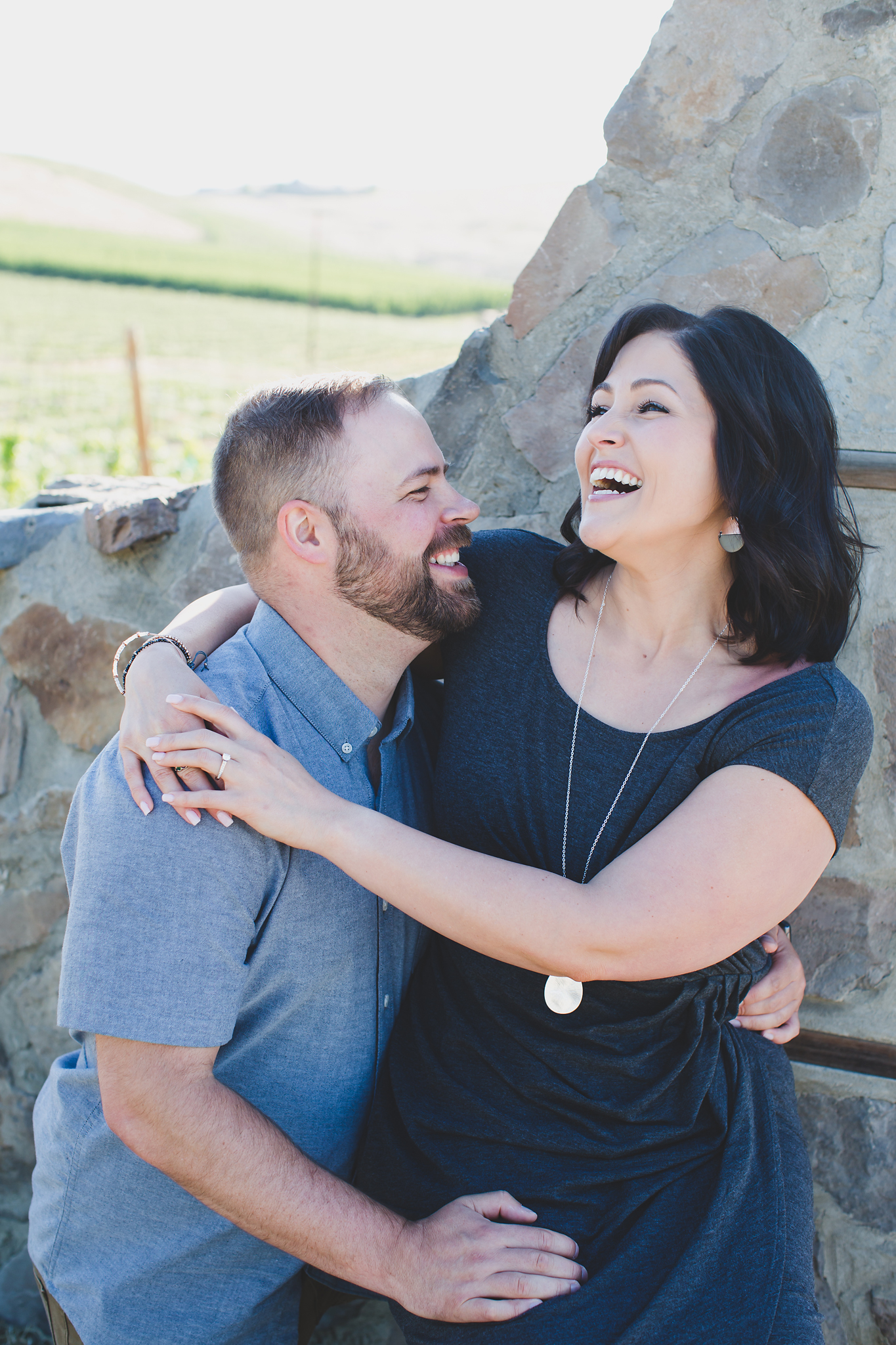 Engaged couple laughing in front of a stone gate at Treveri Cellars in Yakima