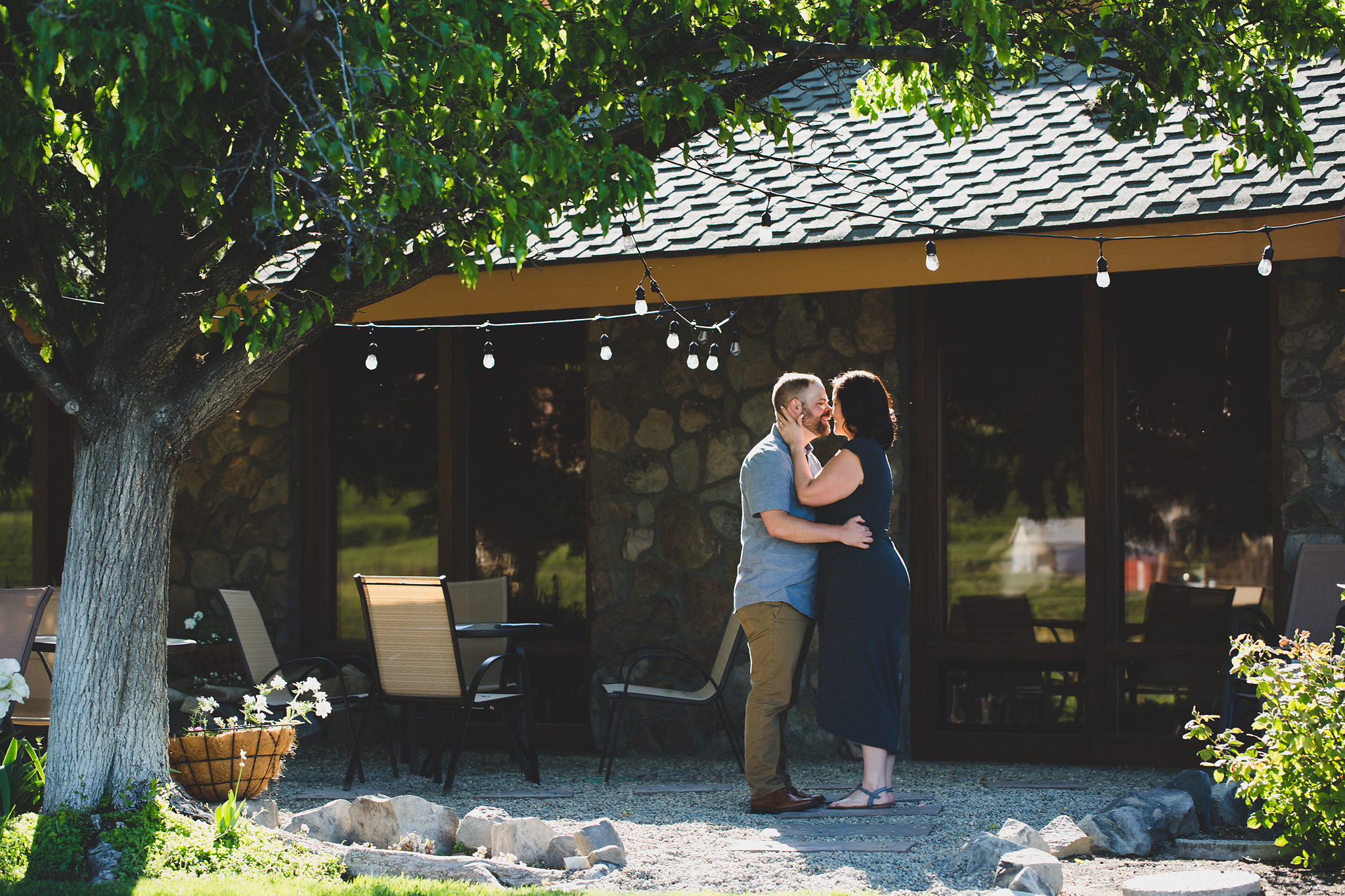 Engaged couple kissing under string lights at Treveri Cellars in Yakima