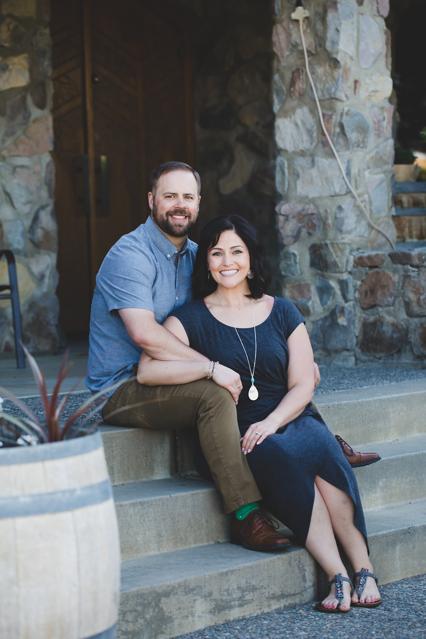 Engaged couple sitting on the steps smiling at Treveri Cellars in Yakima