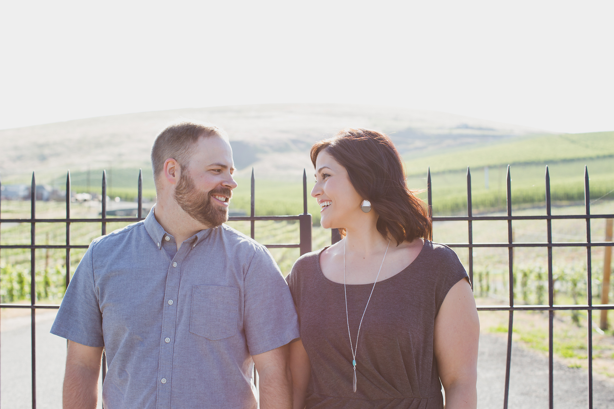 Engaged couple laughing in front of a metal gate at Treveri Cellars in Yakima